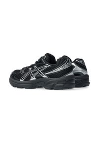 Chaussures de sport noires avec une tige en mesh texturé, des accents argentés, un col rembourré et une semelle en caoutchouc durable, présentant un design à bout arrondi.
