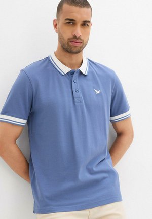 Polo bleu avec col et accents de manches blancs, patte de boutonnage, et un petit logo sur la poitrine. Texture de tissu lisse.