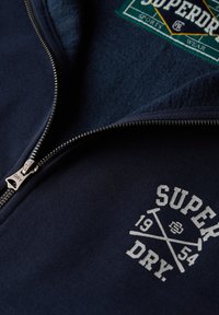 Marine sweatshirt met een rits aan de voorkant. Zachte stof en fleece binnenzijde. Heeft een wit logo met gekruiste honkbats en het jaar 1954.