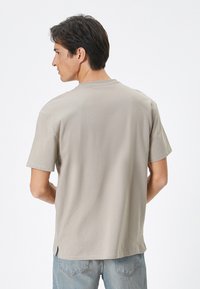 Lys grå crew-neck t-shirt lavet af blødt materiale, med korte ærmer og sideslids ved kanten for let bevægelse.