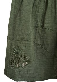 Jupe en lin vert avec une surface texturée et un motif de fraise brodé, agrémentée d'un détail en mesh au niveau de l'ourlet.