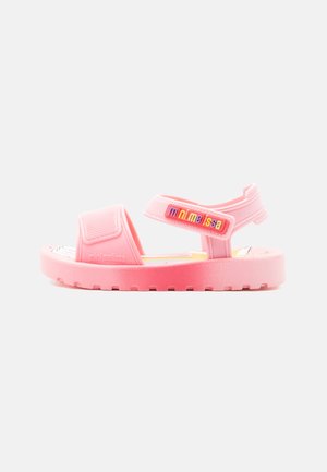 Lyserød åben-tå børnesandal med justerbare remme, flad sål og "mini melissa" branding på siden og remmen.
