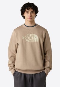 Beige sweatshirt med rund hals, præget med stort logo. Blødt stof, afslappet pasform, ribbede manschetter og talje.