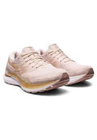 Baskets de sport rose clair avec un dessus texturé, des accents dorés et une semelle intermédiaire blanche. Comprend un col rembourré et une semelle extérieure à motifs.