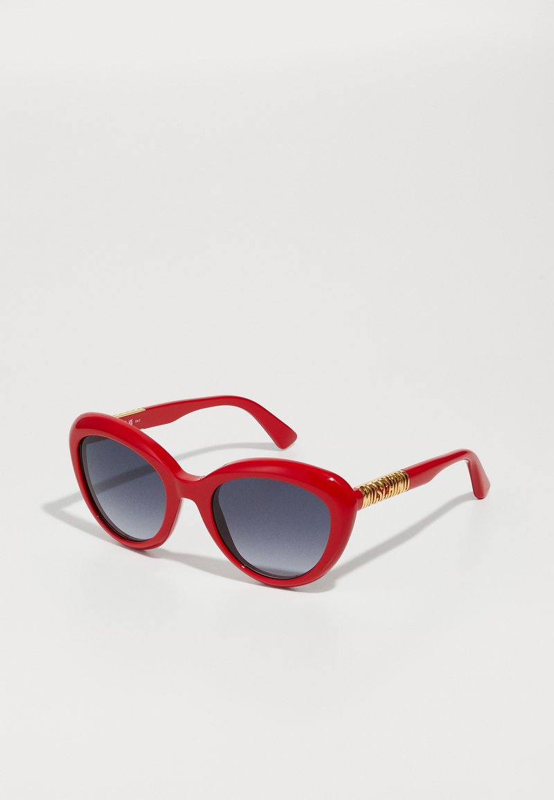 Red plastic sunglasses with oversized, rounded lenses and gradient gray tint. Gold accents on side temples, smooth texture throughout.