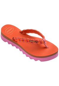 Flip-flop portocalie cu bretele împletite, talpă texturată și o talpă roz ondulată. Prezintă un mic logo auriu "Havaianas" pe bretea.