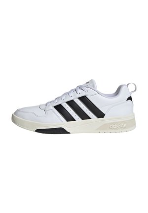 Sneaker Adidas bianca low-top con tre strisce nere, chiusura con lacci frontale e suola beige mostrata dal lato esterno.