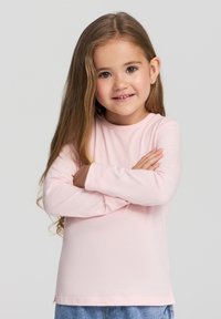 Koszula z długim rękawem w jasnoróżowym kolorze, wykonana z bawełny, z okrągłym dekoltem i luźnym krojem, charakteryzująca się gładką teksturą i podwójnym szwem na brzegach.