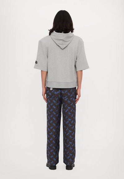 Gray cropped hoodie with a hood and short sleeves, paired with patterned brown pants featuring blue lines, shown from the back.