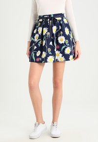 Floral-patterned navy skirt with white daisies, pink and yellow accents. Features a fitted waist and flared design, made of lightweight fabric.