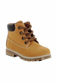 Stivaletti alla caviglia in suede beige con dettagli in pelle nera, lacci marroni, cuciture decorative e suola in gomma robusta. Progettati per una calzatura durevole.