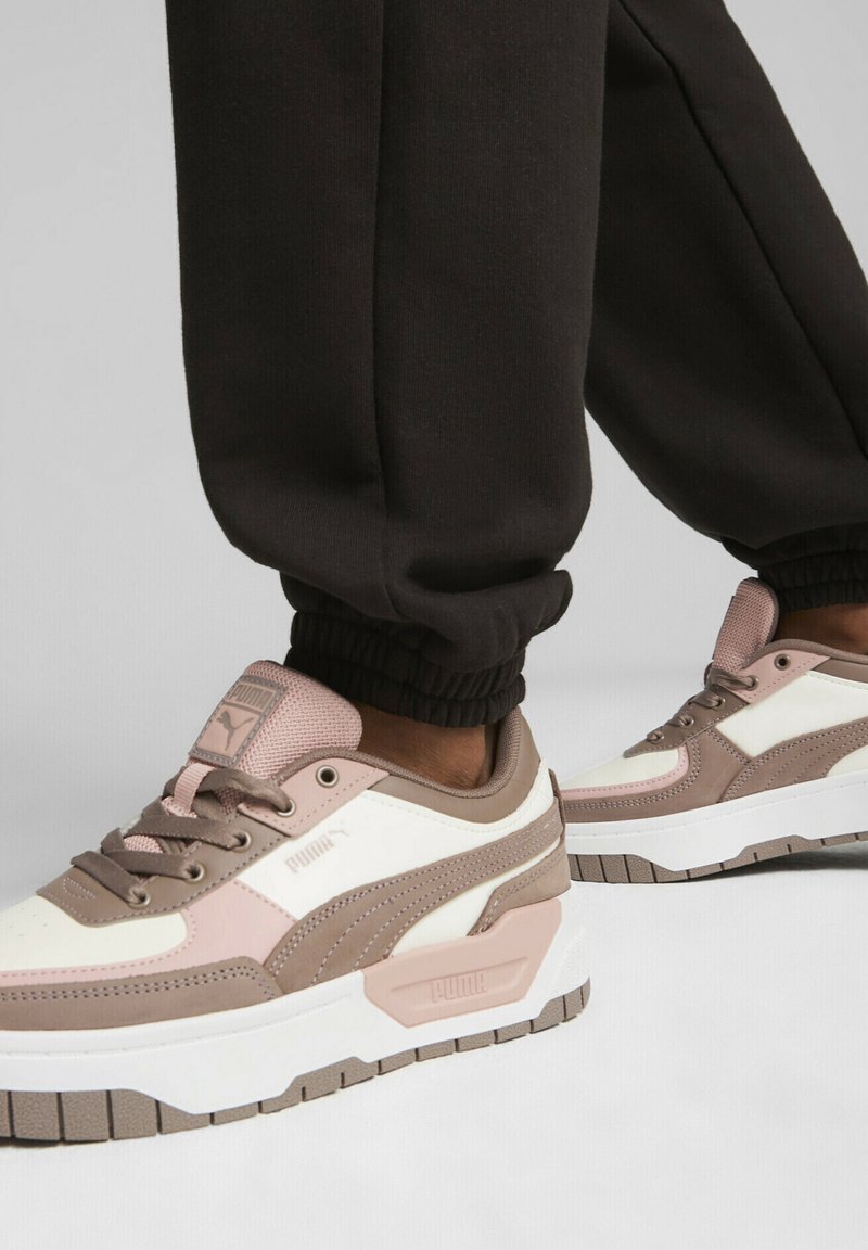 PUMA-sneakers med en blandning av vita, ljusrosa och beige material, med texturerade överdrag, snören och en tjock vit gummisula.