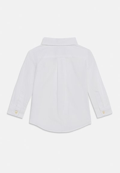 Λευκό πουκάμισο με μακριά μανίκια, προβολή από πίσω, με διπλωμένο γιακά, μία πτυχώση στην πλάτη και μανσέτες με κουμπιά.