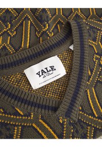 Maglione verde a motivi con design geometrici gialli. Collo a costine con righe navy. Etichetta con la scritta "YALE", in collaborazione con l'Università di Yale.