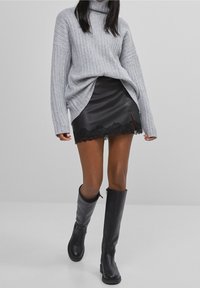 Grå räfflad polokrage tröja, svart fejk läder mini kjol med spetskant, och knä-höga svarta läderstövlar.