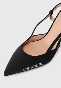 Pumpuri negre cu vârful ascuțit, dintr-un material textil neted, curea pentru gleznă ajustabilă și cu textul "LOVE MOSCHINO" în alb pe lateral.