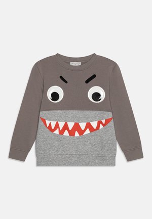 Grijze sweatshirt met een haaiontwerp, voorzien van grote plastic ogen, zwarte wenkbrauwen en rode tanden op een grijze inzet. Lange mouwen.