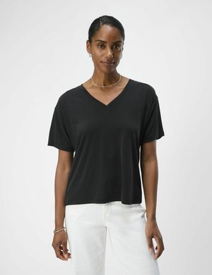 Czarny t-shirt z dekoltem w serek i krótkim rękawem, wykonany z miękkiego materiału. Posiada luźny krój, zestawiony z białymi spodniami w stylu casual.