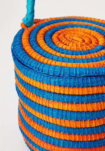 Round woven basket featuring alternating blue and orange stripes, crafted from textured material with a smooth handle.