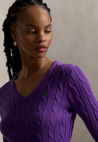 Μωβ πουλόβερ με V-λαιμόκοψη και σχέδιο πλεξούδας, με ριγέ άκρες· διαθέτει ένα μικρό πράσινο λογότυπο στο στήθος· υφασμάτινο με υφή πλεξίματος.