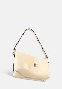 Beige leren schoudertas met een gebogen vorm en een gestructureerd oppervlak, met een goudkleurig accent en een decoratieve sluiting.