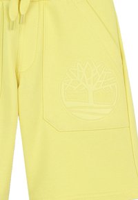 Pantaloni shorts gialli realizzati in tessuto testurizzato, dotati di tasca laterale e un design con logo di un albero in rilievo. Vita con cordoncino per una vestibilità regolabile.