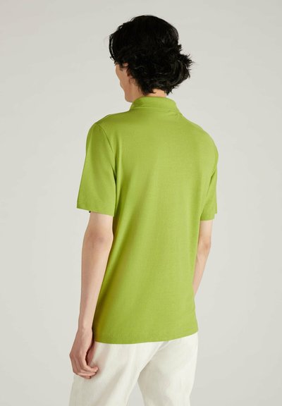 Polo de manga corta verde lima hecho de una tela suave, que cuenta con un collar y un corte holgado, con costuras visibles y un diseño sencillo.