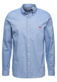 Chemise à manches longues bleu clair avec boutons, col boutonné et petit logo Levi’s rouge sur la poitrine, présentée de face sur fond blanc.