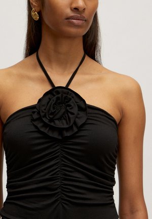 Zwarte haltertop met een gerimpelde textuur en een gelaagde stoffen bloemdetail in het midden, voorzien van een dunne verstelbare band.