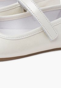 Bailarinas de cuero blanco tipo Mary Jane con un acabado liso, una sola correa en el empeine y una suela de goma marrón clara.