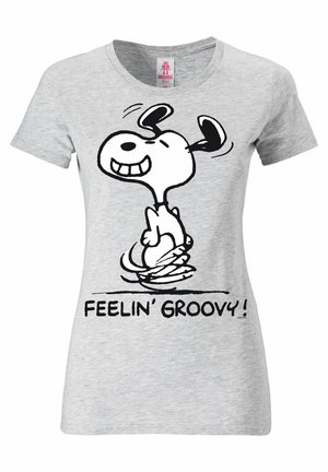 T-shirt en coton gris avec un chien en cartoon noir arborant une expression joyeuse, entouré du texte "FEELIN' GROOVY!" en lettres noires.