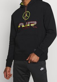 Svart hoodie med stort, färgstarkt "AIR"-tryck med rutig design, dragsko i huvan och känguruficka.