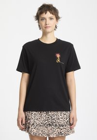 Camiseta de algodón negra de manga corta, con un gráfico colorido de un sol y una lagartija en el pecho. Diseño simple y de corte holgado.