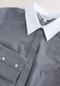Striped shirt featuring a gray background with white vertical stripes, buttoned cuffs, and a contrasting white collar. Tag on collar visible.