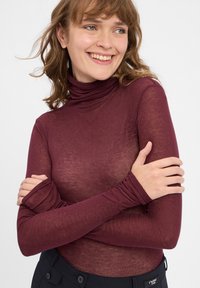 Burgundské dlhé rukávy s rolákom vyrobené z ľahkej, priesvitnej látky; priliehavý strih s predĺženými rukávmi a pohodlným golierom.