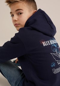 Felpa blu navy con stampa grafica floreale sul retro, con testo bianco e colorato. Realizzata in morbido tessuto di cotone, vestibilità casual.