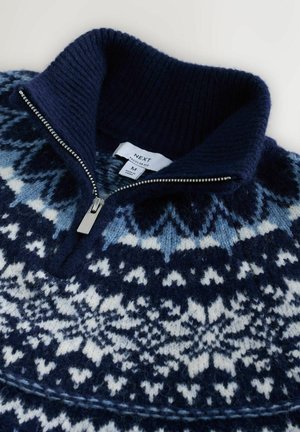 Navyblauwe gebreide pullover met een ritssluiting bij de kraag. Bevat witte en lichtblauwe sneeuwvlokpatronen. Zacht wollen materiaal, geribbelde kraag.