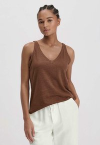 Bruine mouwloze tanktop met een V-hals, gemaakt van zacht materiaal. Heeft een ontspannen pasvorm, subtiele textuur en minimale stikdetails.