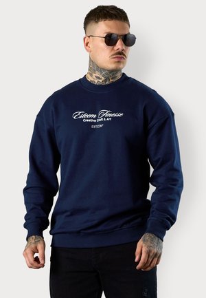 Navy blue sweatshirt made from textured cotton, featuring long sleeves, a crew neck, and white printed logo text on the front.