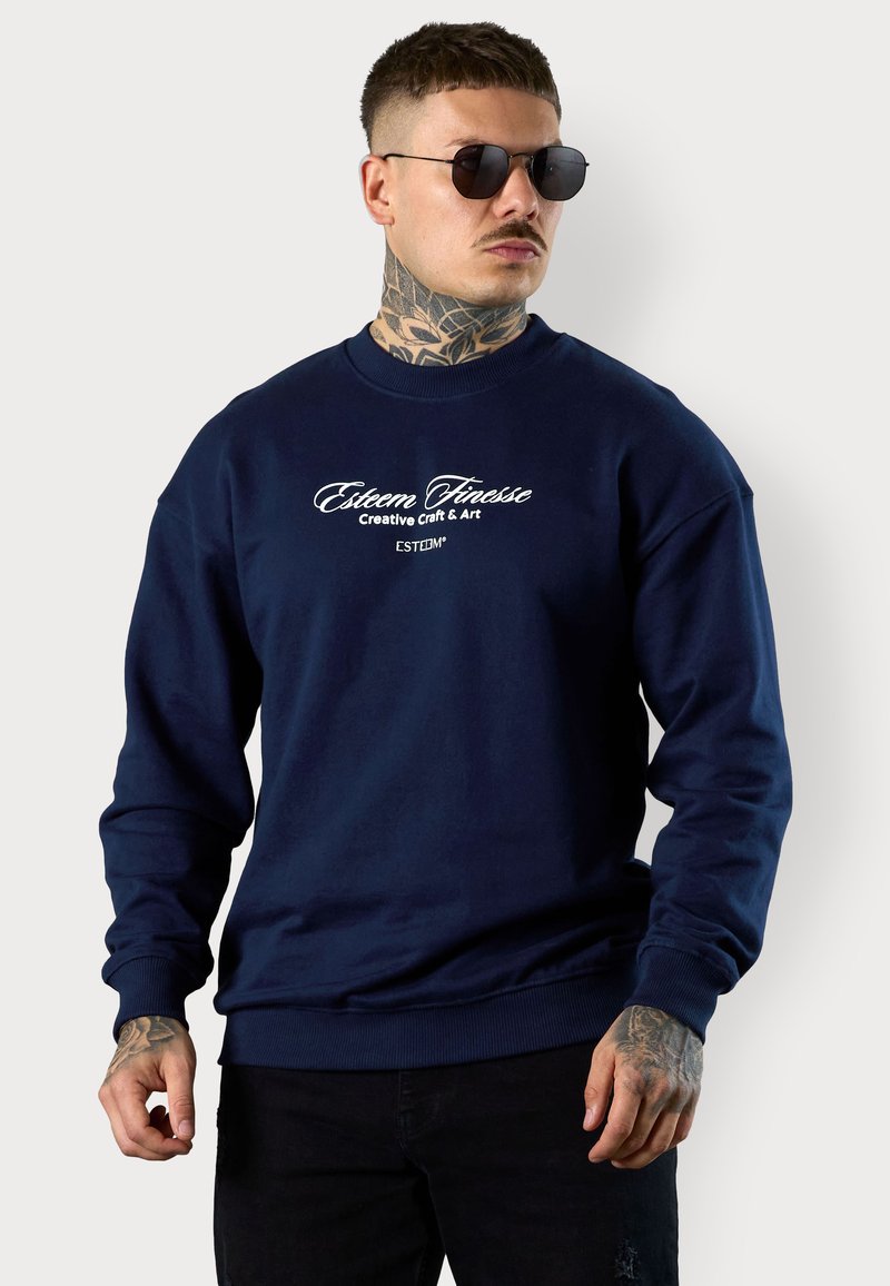 Navy blue sweatshirt made from textured cotton, featuring long sleeves, a crew neck, and white printed logo text on the front.