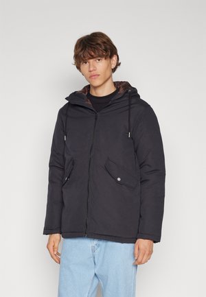 Veste isolante noire avec capuche, dotée d'une fermeture éclair à l'avant, de deux poches avant et d'un intérieur doublé marron. Tissu texturé avec une finition mate.