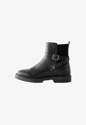 Must musta ankle boot musta elastsete külgpanelid, pandla detail ja tekstuuriga kangast krae. Lame tald koos õmbluse aktsendiga.