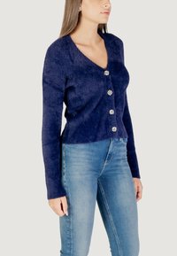 Cardigan blu navy con scollo a V, maniche lunghe, tessuto texturizzato e cinque bottoni decorativi a forma di fiore sul davanti.