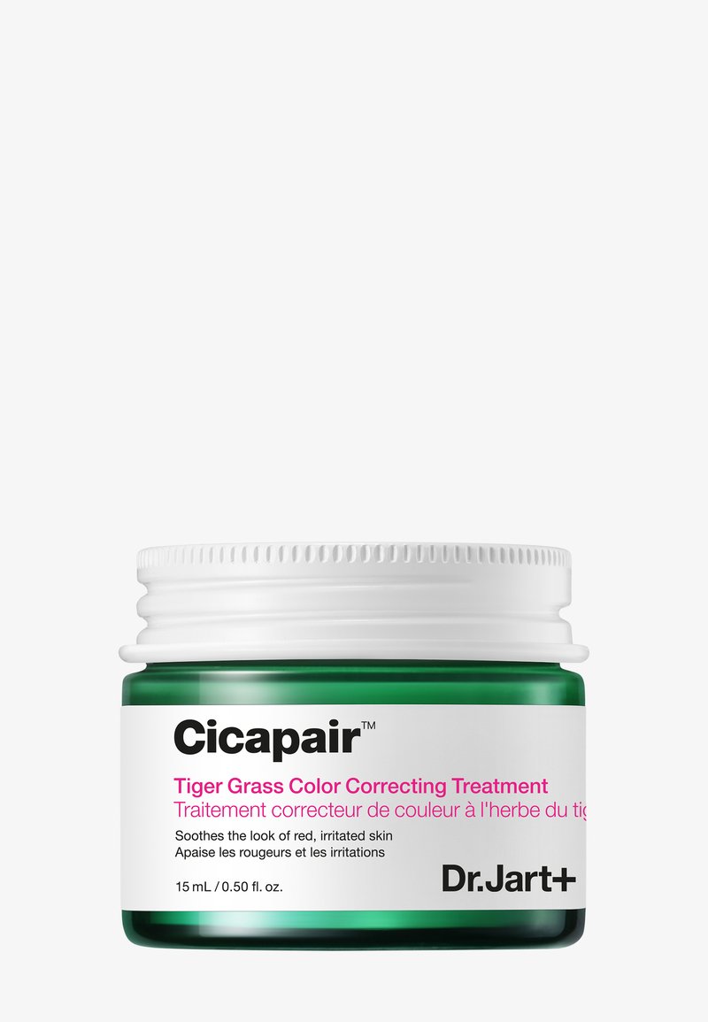 Groene glazen pot met een witte schroefdop. Het etiket bevat roze en zwarte tekst en beschrijft een kleurcorrigerende behandeling voor geïrriteerde huid. 15 ml.