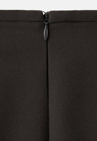 Tissu noir avec une texture lisse, doté d'une fermeture éclair au centre en haut. Le design est simple et ajusté.