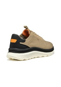 Scarpa sportiva beige con tomaia in tessuto testurizzato, accenti in gomma nera e interno arancione. Presenta una suola spessa e imbottita.