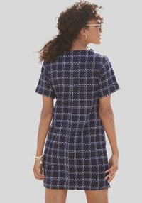 Marineblaues Kleid mit kurzen Ärmeln, kariertem Muster in Weiß, strukturiertem Stoff, knielang, runder Halsauschnitt und lockerer Passform.