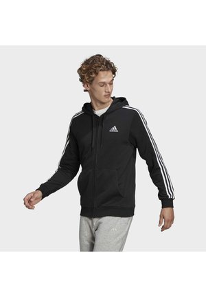 Felpa nera con zip, con accenti a tre strisce bianche sulle maniche, presenta una tasca frontale e un cappuccio con cordino, realizzata in tessuto morbido.