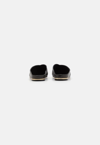 Sorte lær slip-on sko med lav profil og afrundede kanter, der har en guldaccent på sålen for ekstra detaljer.