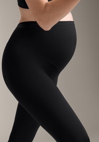 Fekete kismama leggings magas derékkal, sima, rugalmas anyagból készült, amely zökkenőmentesen alkalmazkodik a növekvő hashoz.